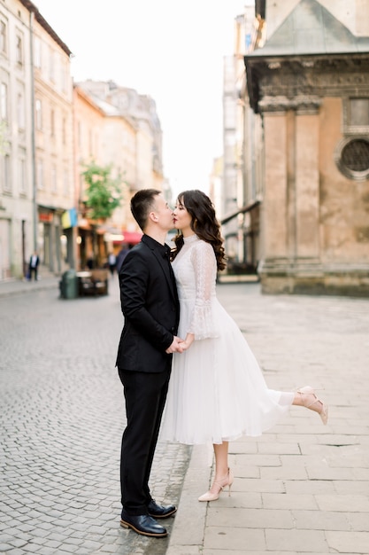 Le coppie asiatiche adorabili camminano e baciano nella città. l'uomo è in abito di lusso nero, la donna in abito bianco elegante