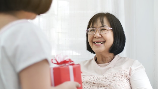 Foto la bella ragazza asiatica offre una scatola regalo spaziale a sua nonna