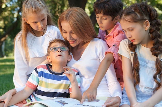 Bella bella donna che gode della lettura ai suoi studenti all'aperto nel parco