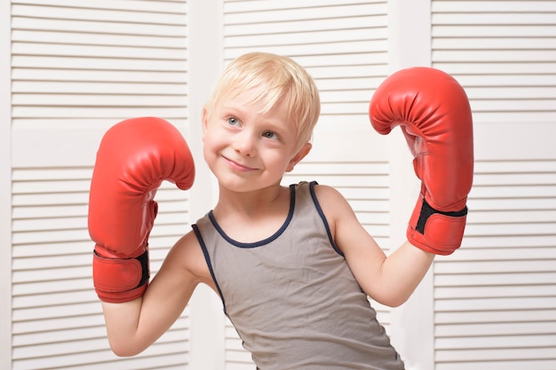 Lovely blond boy in red boxing gloves. 