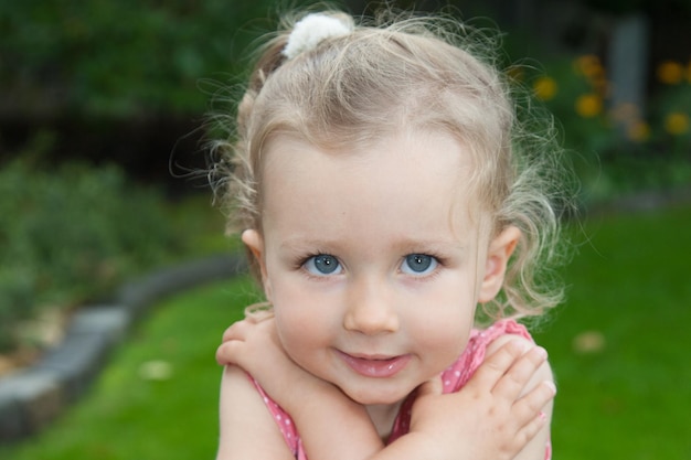 Lovely blond child girl posing outdoor with blue eyes