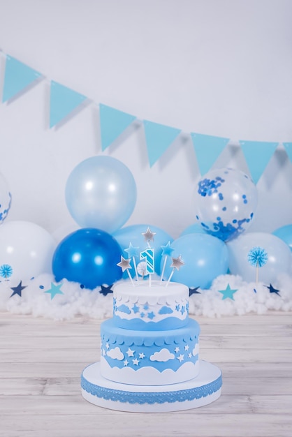 Lovely blue and white birthday cake whit colored balloons and stars Boy birthday celebration 1st