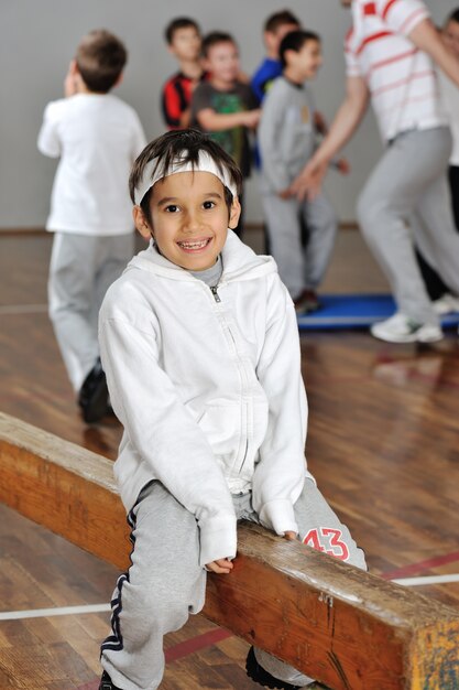 Lovely boy in front of his friends and trainer in gym hall