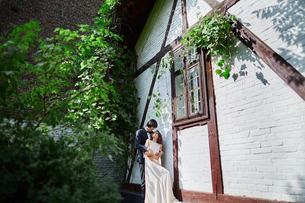 Lovely bride and bridegroom standing close to each other at park background, wedding photo, beautiful couple.