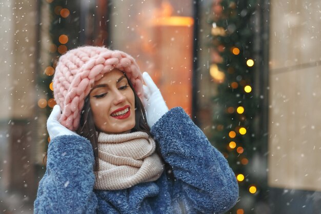 写真 雪の降る天気で街を歩いているコートを着た素敵なブルネットの女性。空きスペース