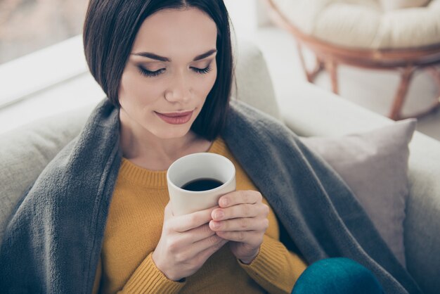 一杯のコーヒーと屋内でポーズをとる素敵なブルネットの女性