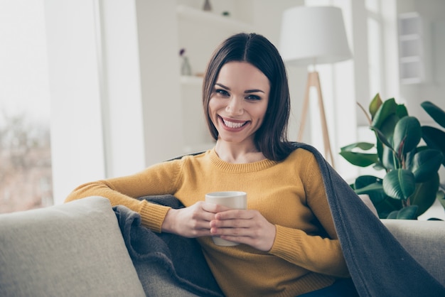 一杯のコーヒーと屋内でポーズをとる素敵なブルネットの女性