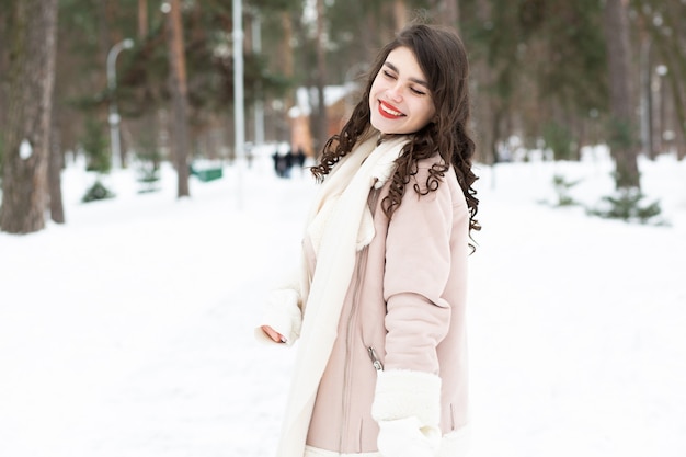 Lovely brunette woman walking in the forest in winter. Space for text