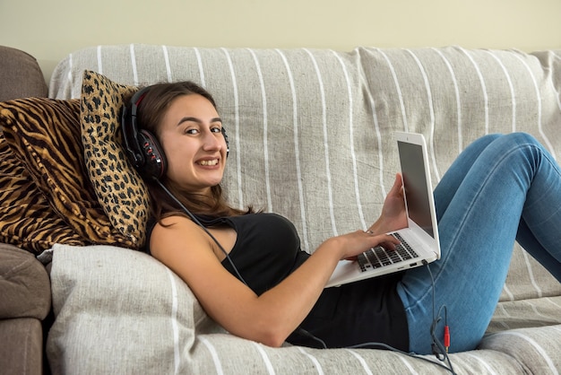 Lovely calm woman using digital tablet while sitting on sofa in living room