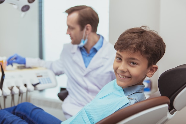 彼の矯正歯科医による歯科検診を待っている笑顔、素敵な陽気な少年