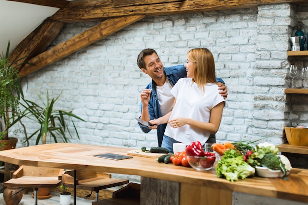 Lovely cheerful couple cooking dinner together and having fun at rustic kitchen