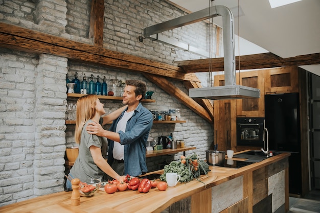 Lovely cheerful young couple cooking dinner together and having fun at rustic kitchen