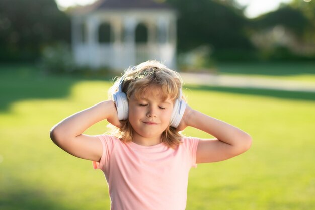 Lovely child enjoying music through headphones expressing true positive emotions of fashionable happ