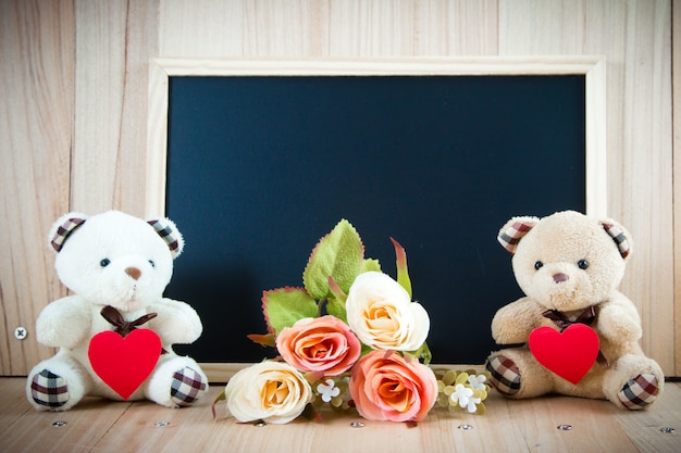 Lovely couple bear hold red heart sit near sweet roses and blackboard on floor, valentine concept