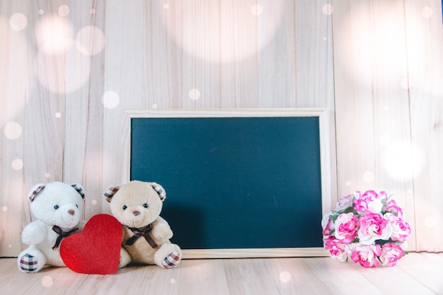 Lovely couple bear sit near blackboard and sweet roses on floor, valentine concept