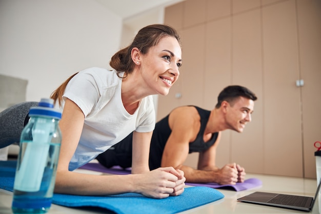 Lovely couple doing plank pose during home workout