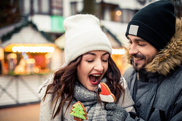 Lovely couple hold gingerbread at winter fair