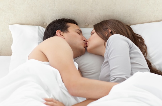 Lovely couple kissing in each other's arms on the bed 