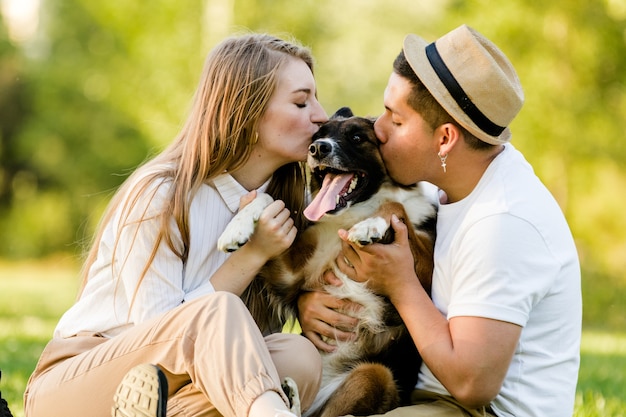 공원에서 웃는 개를 키스하는 멋진 커플