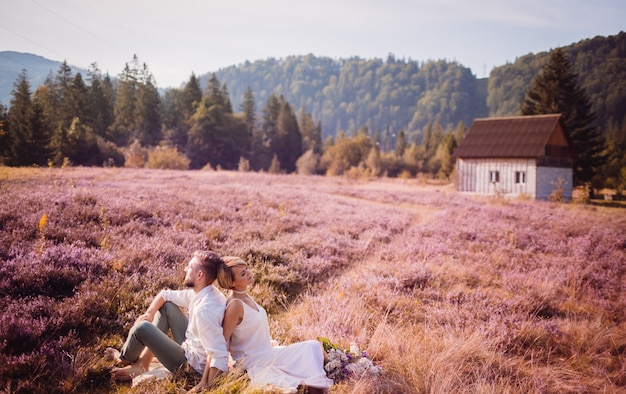 The lovely couple in love embracing and sitting  on the grass