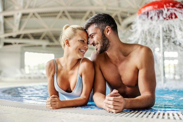 A lovely couple in the pool with thermal water is flirting and enjoying time together