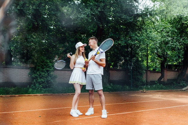 Lovely couple relaxing after playing game of tennis outside in summer. Talking about life.