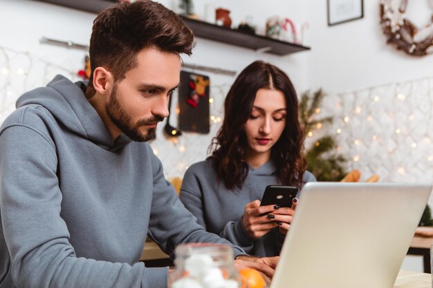 Bella coppia seduta cucina uso laptop acquistare regali in internet ghirlande casa accogliente interno