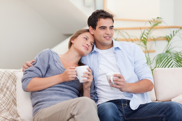 Lovely couple watching TV while drinking tea