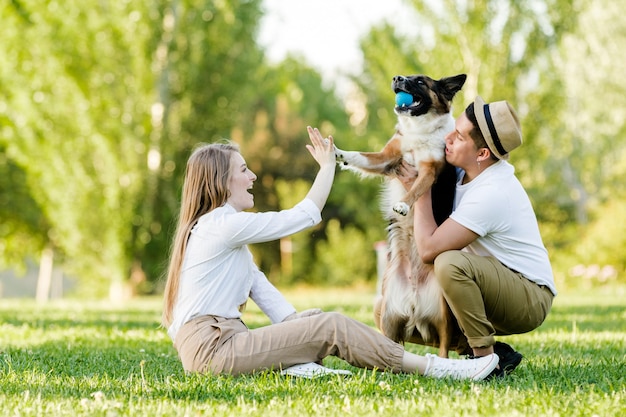 Прекрасная пара с собакой веселятся в парке