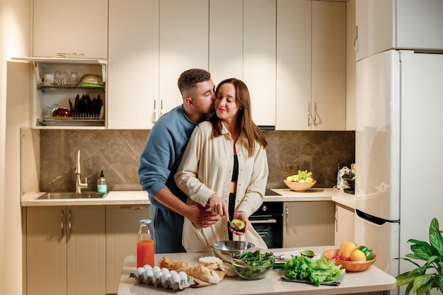 Lovely family couple preparing vegetable vegan salad together\
in kitchen healthy food and diet concept lifestyle cook at\
home