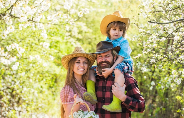 Lovely family outdoors nature background Ranch concept Happy family day Mother father and cute son Family farm Farmers in blooming garden Parents growing little baby Spend time together