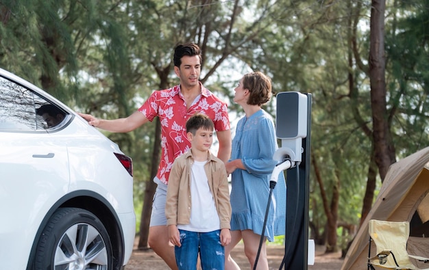 Photo lovely family recharge ev car with ev charging station in campsite perpetual