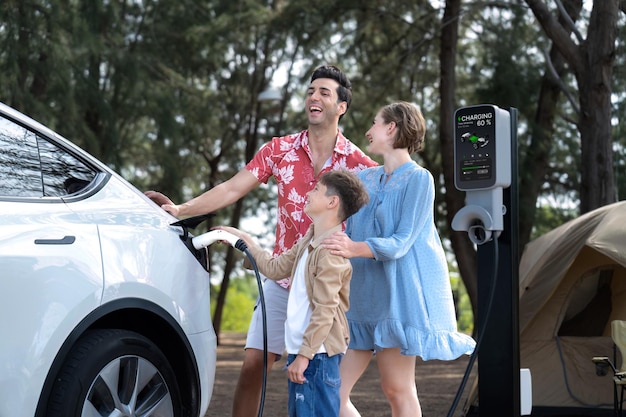 Photo lovely family recharge ev car with ev charging station in campsite perpetual