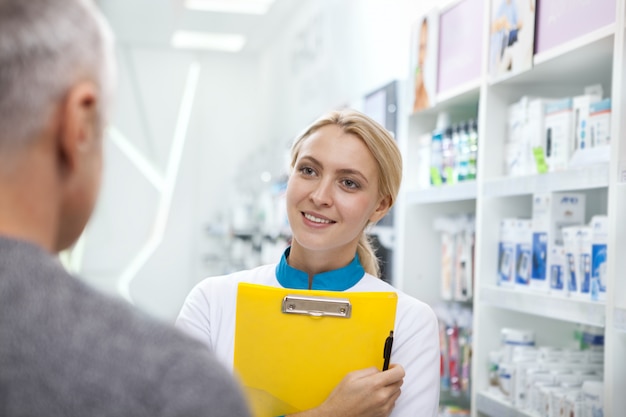 Lovely female pharmacist helping her client