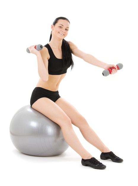 lovely fitness instructor with dumbbells on pilates ball