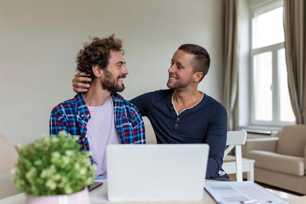 Lovely gay couple laughing together while sitting in their\
living room at home two romantic young male lovers having fun\
surfing the internet indoors young gay couple living together