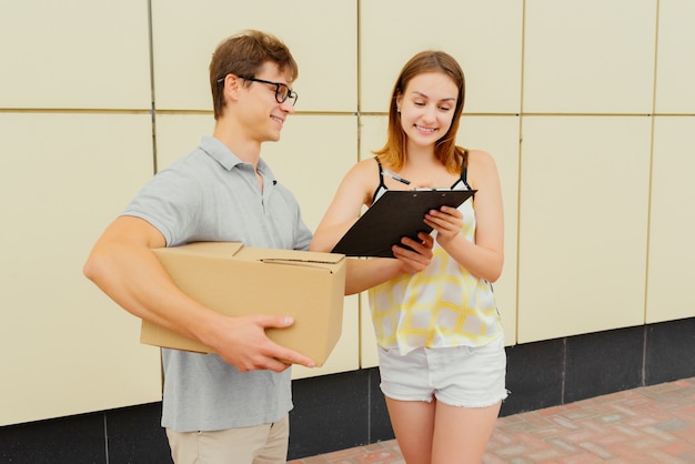 Lovely girl giving a signature of delivery package, outside