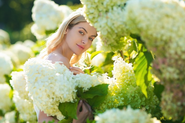 Lovely girl standing on soft background hydrangea blossoming flowers tenderness portrait of a very b