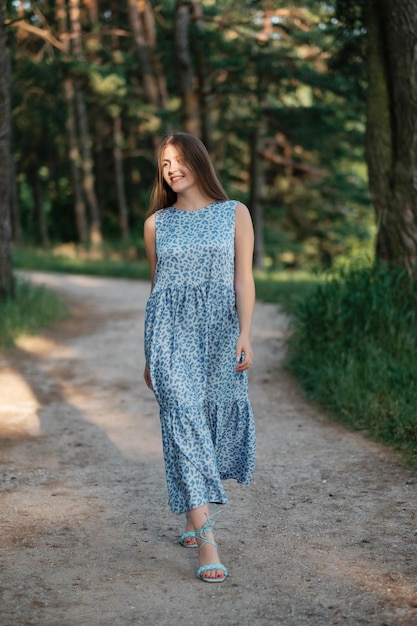 Bella ragazza in abito estivo a piedi strada forestale