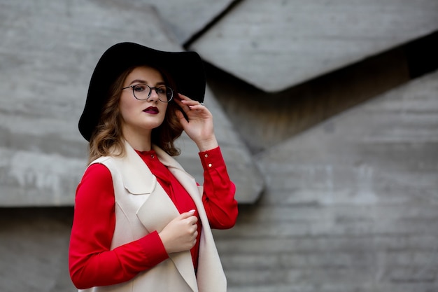 Lovely girl wearing hat and sunglasses posing in the autumn park. Space for text