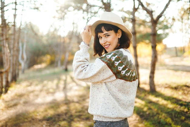 숲에서 일몰에 아름다운 미소를 지닌 사랑스러운 소녀 그 소녀는 모자를 쓰고 있다