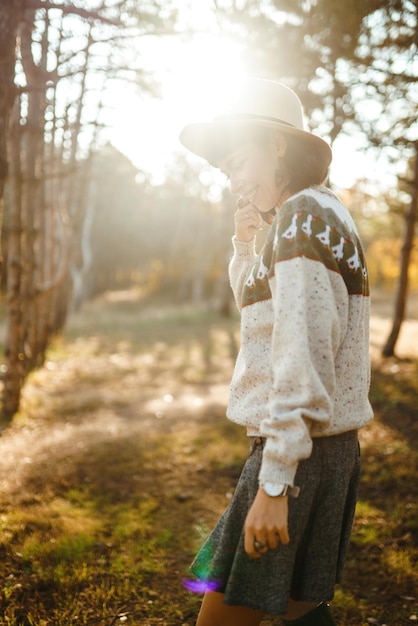 Lovely girl with a beautiful smile at sunset in the forest The girl is dressed with a hat