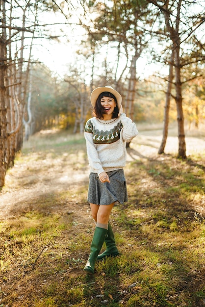 Lovely girl with a beautiful smile at sunset in the forest The girl is dressed with a hat