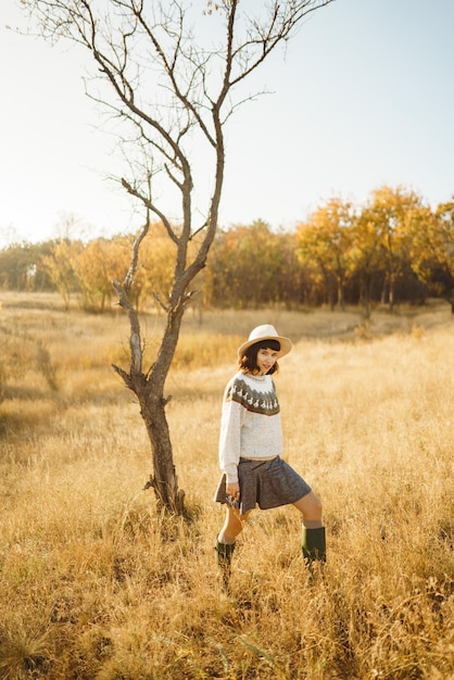 Lovely girl with a beautiful smile at sunset in the forest The girl is dressed with a hat