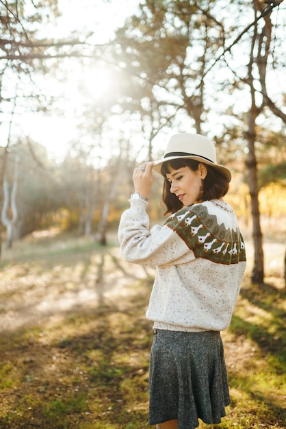 Lovely girl with a beautiful smile at sunset in the forest The girl is dressed with a hat