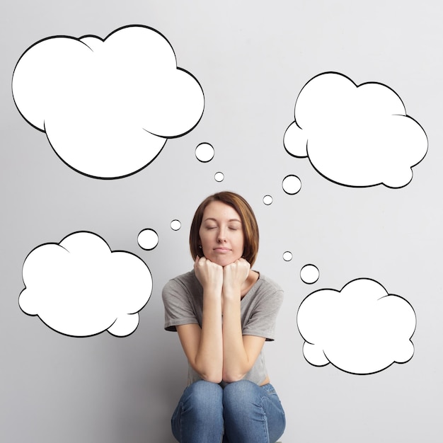 Photo lovely girl with short hair sitting against the wall and dream about the future painted clouds for text