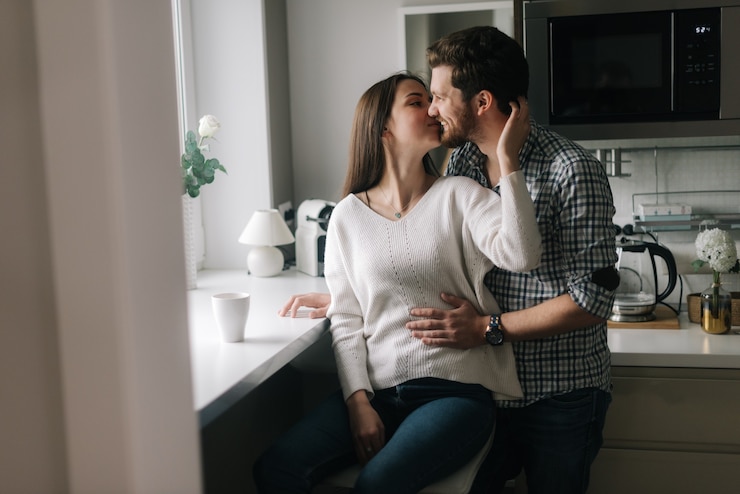 Photo lovely happy couple is kissing on the kitchen by the window