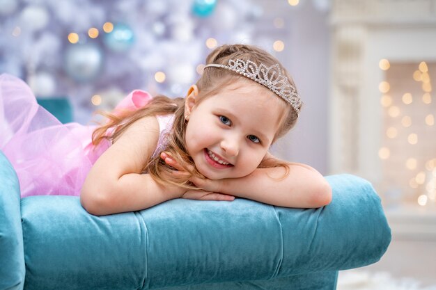 Photo lovely happy girl in beautiful dress lies on sofa