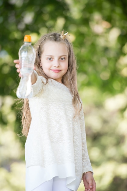 Прекрасная счастливая маленькая девочка пьет воду в летний день