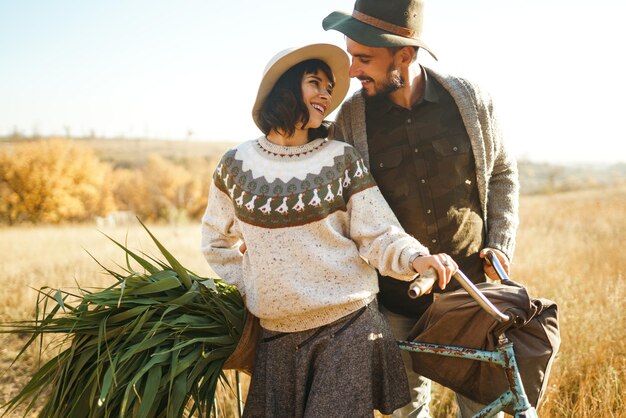 Photo lovely hipster couple with bike couple wearing beautiful hats and sweaters lifestyle